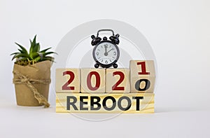 Business and 2021 new year reboot symbol. Fliped wooden cube and changed words `reboot 2020` to `reboot 2021`. Alarm clock, pl