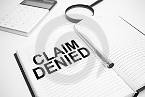 Business accessories, calculator,reports and magnifier glass with text Claim Denied