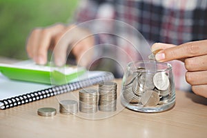 Business accounting with saving money with hand putting coins in jug glass, Businessman Writing Financial Accounting, concept
