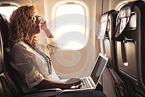 Il negozio un adulto bellissimo riccio bionda una donna viaggio sul un aereo collegato sul rete informatica mondiale computer portatile sul 