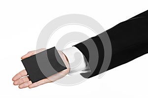 Business and advertising topic: Man in black suit holding a black blank card in hand isolated on white background in studio