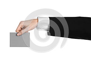 Business and advertising topic: Man in black suit holding a gray blank card in hand isolated on white background in studio