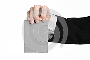 Business and advertising topic: Man in black suit holding a gray blank card in hand isolated on white background in studio