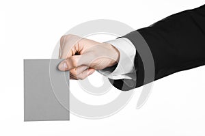 Business and advertising topic: Man in black suit holding a gray blank card in hand isolated on white background in studio