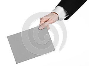 Business and advertising topic: Man in black suit holding a gray blank card in hand isolated on white background in studio