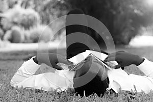 Business african man lying sleep after reading book on a green meadow in black and white style.Concept of recreation
