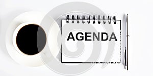 Business agenda, planning concept. Spiral notebook with Agenda text on the white background with coffe