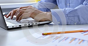 Business analytics - man working with financial reports at office on laptop computer