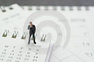 Business appointment, office meeting calendar, miniature businessman thinking and standing on pile of desktop calendars photo