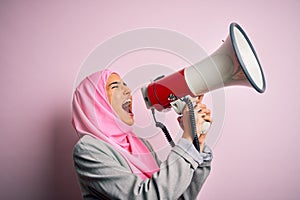 Business arab woman wearing hijab shouting angry on protest through megaphone