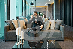 Business Asian man using a smartphone on sofa in luxury condo