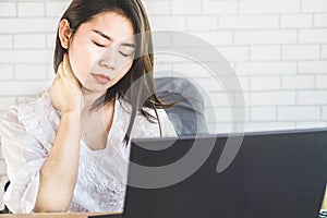 Business Asian woman having neck and shoulder pain while working on computer