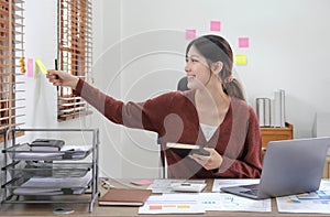 Business asian woman taking note on sticky note, Attractive girl working with laptop computer