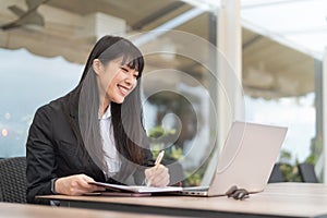 Business Asian woman working on computer in cafe outdoor - Young female entrepreneur using laptop in office