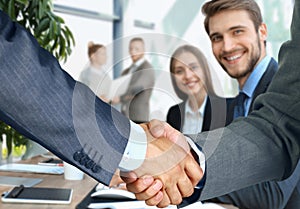 Business associates shaking hands in office.