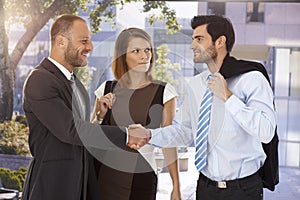 Business associates shaking hands on the street