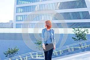 Business attractive woman walking down the street on a background of a skyscraper