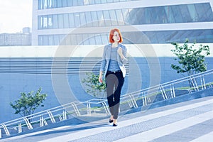 Business attractive women walking down the street on a background of a skyscraper