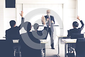 Business Audience raising hand up while businessman is speaking in training for Opinion with Meeting Leader in Conference Room