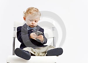 Bambino vestito in abbigliamento commerciale sms su di un telefono intelligente.