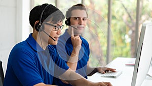 Business background of asian and caucasian male customer service agents on telephone service to customers at helpdesk call center