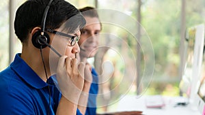 Business background of asian and caucasian male customer service agents on telephone service to customers at helpdesk call center