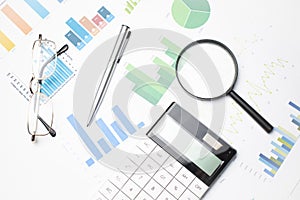 Business background, financial data concept with pen and magnifying glass