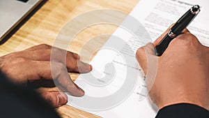 Business background of hand holding pen signing contract paper on desk