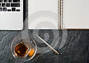 Business background with laptop and notepad on black stone background.