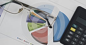 Business background. Rotation of glasses and a calculator lying on a colored diagram. Concept of success