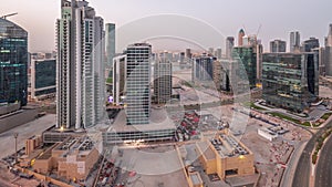 Business Bay Dubai skyscrapers with water canal aerial night to day timelapse.