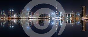 Business bay skyline with reflection in the water at night, Dubai, UAE