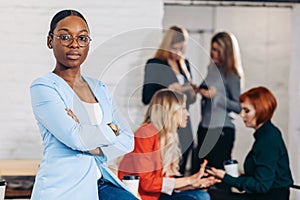 Business black woman adjusting her clothes on a grey background