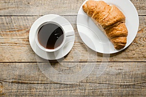 Business breakfast in office with coffee and croissant on wooden table background top view mockup