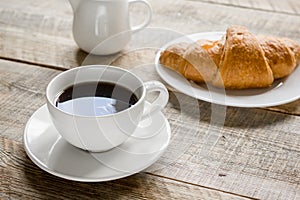 Business breakfast in office with coffee, milk and croissant on wooden table background