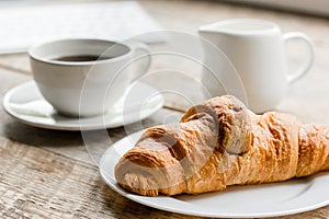 Business breakfast in office with coffee, milk and croissant on wooden table background