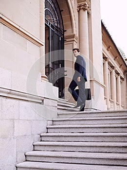 Business, briefcase and man walking into law firm in city with evening commute, stairs and court building. Businessman