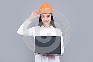 Business builder woman with laptop computer, portrait on gray. Portrait of female worker in hardhat helmet.