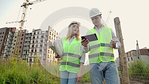 Business, building, industry, technology and people concept - smiling builder in hardhat with tablet pc computer along