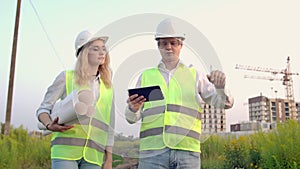 Business, building, industry, technology and people concept - smiling builder in hardhat with tablet pc computer along