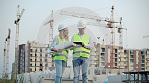 Business, building, industry, technology and people concept - smiling builder in hardhat with tablet pc computer along