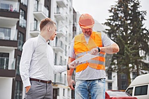 Business, building, teamwork and people concept - group of smiling builders in hardhats at construction site