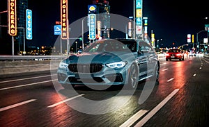 Business car speeds through city highway at night. Front view captures sleek design, headlights cutting through darkness. City