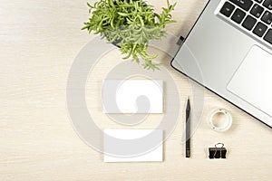 Business card blank, laptop, flower and pencil at office desk table top view. Corporate stationery branding mock-up