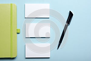 Business card blank, notepad, flower, coffee cup and pen at office desk table top view. Corporate stationery branding