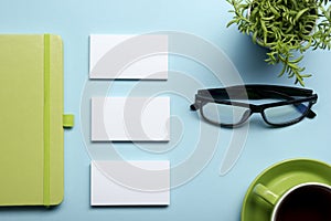 Business card blank, notepad, flower, coffee cup and pen at office desk table top view. Corporate stationery branding