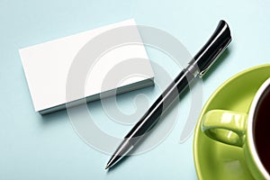 Business card blank over coffee cup and pen at office table. Corporate stationery branding mock-up