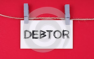 A business card with the inscription - DEBTOR. Isolated on red background