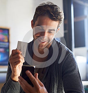 Business card, phone and young man in cafe dial mobile number for communication or call. Smile, contact paper and male