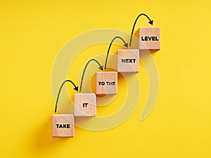 Business career path for growth and success concept. Wooden block ladder with the message take it to the next level with stepping photo